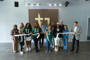 A group of people cutting a grand opening ribbon.