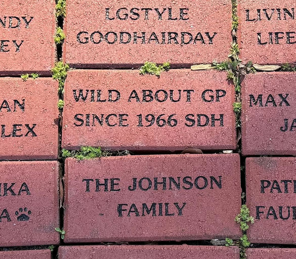 Photo by Grant Park Conservancy on April 02, 2025. Pode ser uma imagem de lápide, parede de tijolos, meio-fio e texto que diz "DY LGSTYLE GOODHAIRDAY LIVIN LIFE LEX WILD ABOUT GP SINCE 1966 SDH MAX THEJOHNSON JOHI HNSON THE FAMILY PAT".
